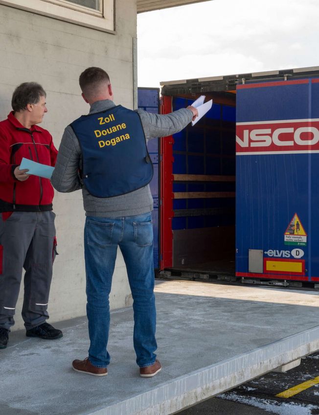Mitarbeiter von Zoll und Spedition auf der Rampe vor einem Transco Lkw