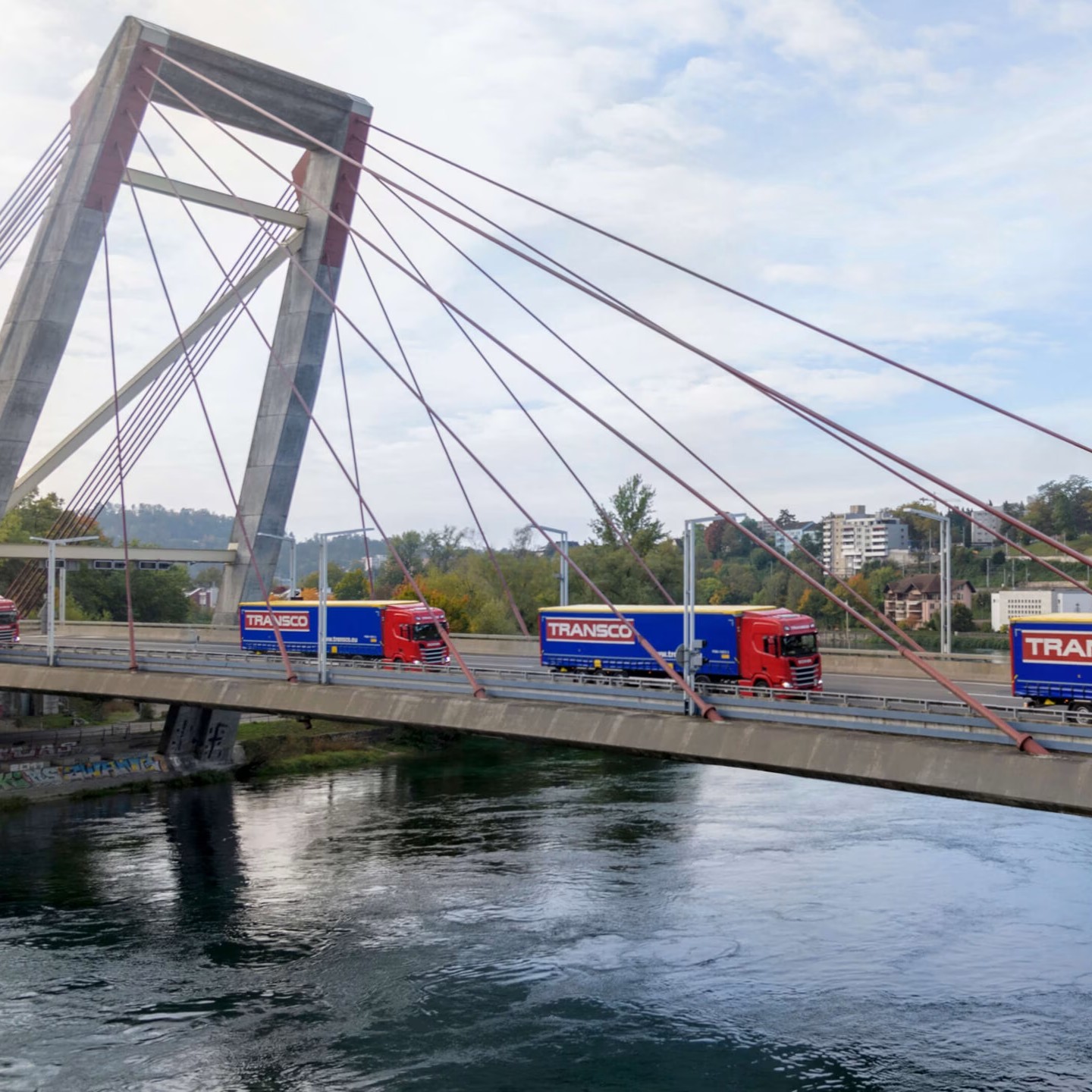 Mehrere Lkw der Spedition Transco fahren über eine Brücke